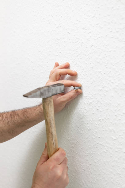 istock worker hammering a nail into the wall 2194664365