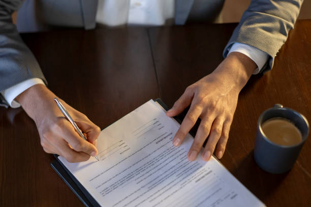 istock Businessman signing a contract at his desk with coffee 2194664725