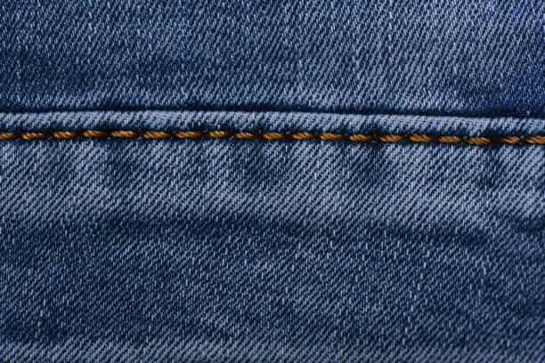 Denim fabric with yellow thread seams, denim jacket, denim pants, for background or fabric sample sale. Thread seam on denim.