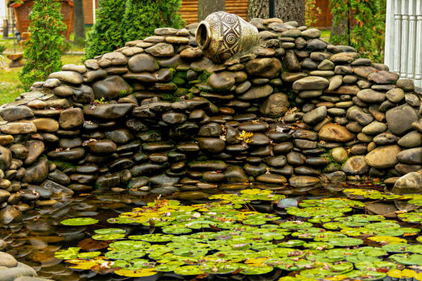A rock wall with a waterfall and a pond with lily pads