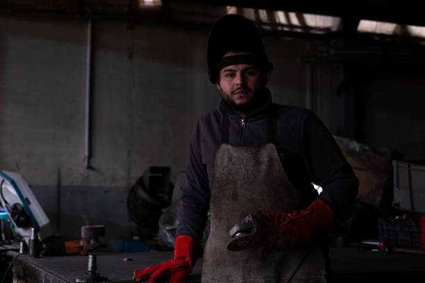 istock Metalworker wearing protective gear holding angle grinder in workshop 2194671798