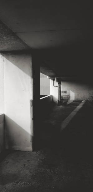 istock Parking in building with sunlight from left side, a water pipeline and darkness in black and white style. Art and Abstract background in monochrome style. 2194673260