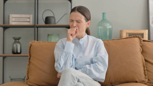 istock Coughing Woman Sitting on Sofa at Home 2194674753
