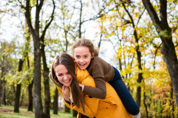 istock Mother and daughter piggy back in park 2194676469