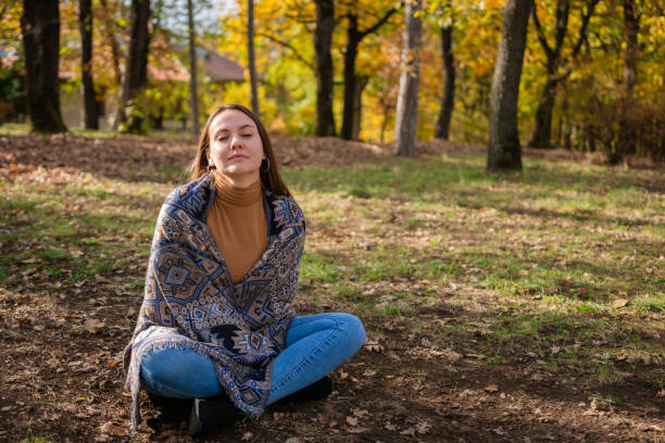 istock A woman with closed eyes enjoys nature while sitting on the ground 2194677792