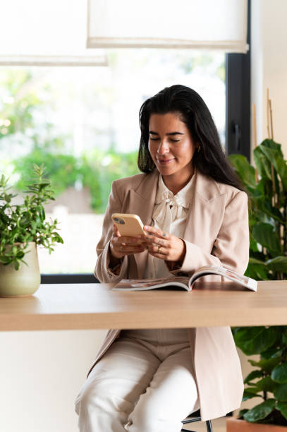 Businesswoman using smartphone and reading magazine at home