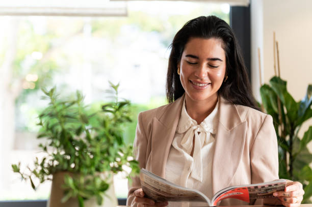 Smiling businesswoman reading magazine during office break