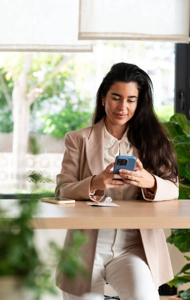 istock Young businesswoman using smartphone in a modern office during brunch break 2194682347