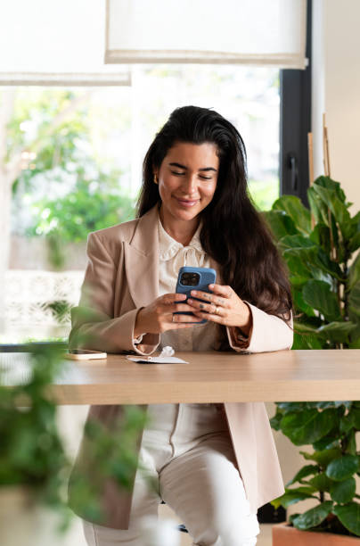 istock Young businesswoman using mobile phone and smiling in modern office 2194682349