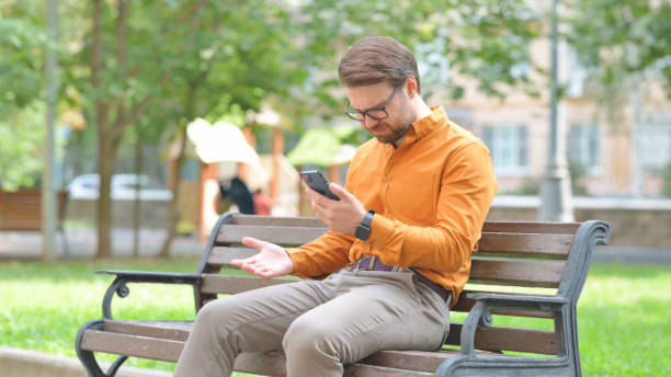 istock Young Man Reacting to Online Loss while Sitting Outdoor 2194686216