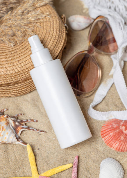 istock Sunscreen spray bottle, sunglasses, towel, starfishes and shells on a sandy beach, cosmetic mockup 2194687583