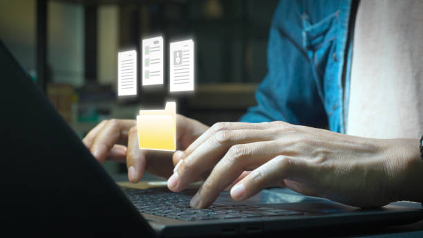 istock Close-up of hands typing on a laptop with holographic digital documents and a folder icon floating above, representing file management, data organization, and online documentation. 2194687666