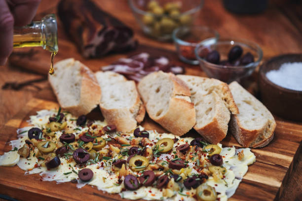 Rustic Butter Board with Olives, Herbs, and Garnishes on Wooden Surface