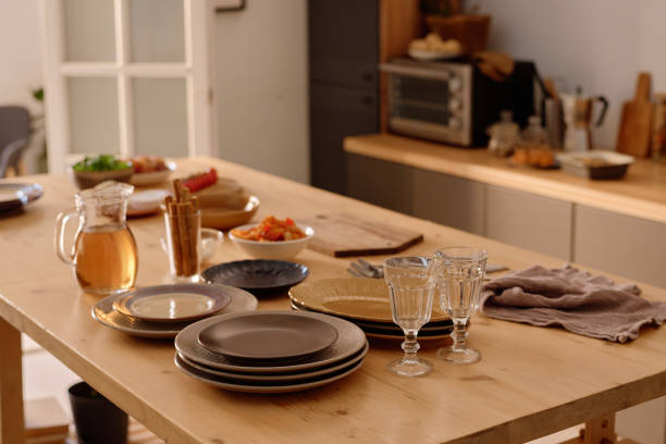 High angle shot of clean plates in stack and polished crystal glasses surrounded with plates full of snack on table top