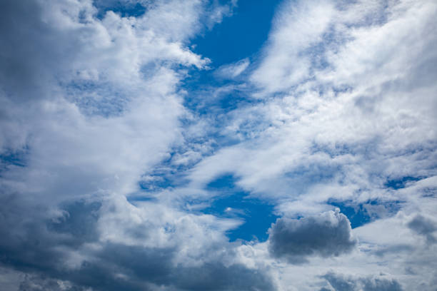 A captivating view of a dynamic sky that is filled with soft white clouds and vibrant patches of blue light