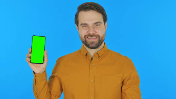 istock Man Holding Phone with Green Screen on Blue Background 2194694383