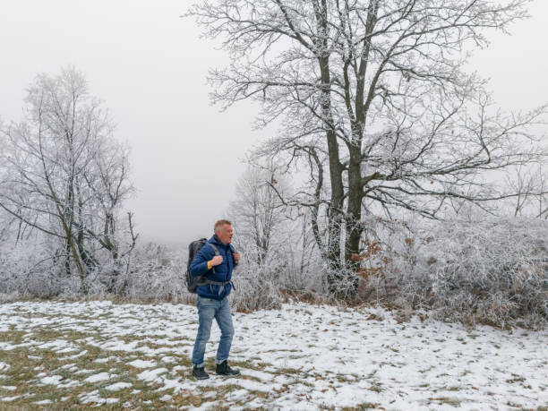 Man hiking on weekend for relaxation and good health on cold winter morning in countryside