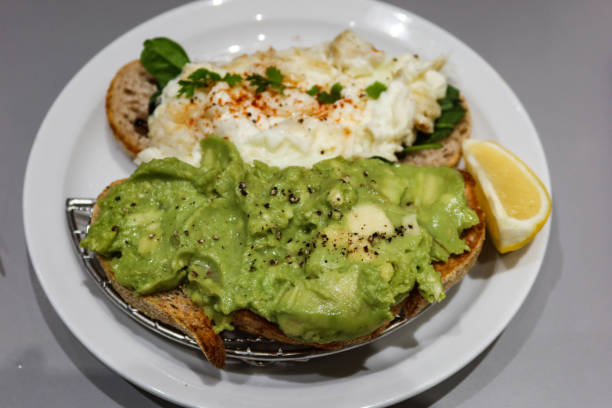 istock \ sourdough bread toast with avocado paste with black pepper and egg white crab meat on another slice. Lemon slice on the side on a white plate 2194699051