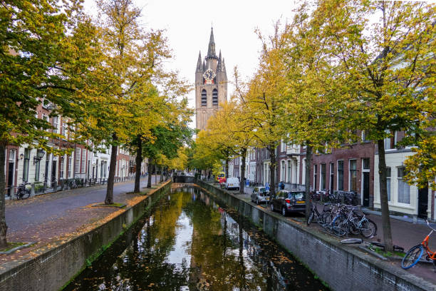 Part of the Oude Delft (Old Delft) canal in the ancient center of Delft in The Netherlands. In the background is the tower of the Oude Kerk (Old Church) and the city is famous for Delftware pottery.