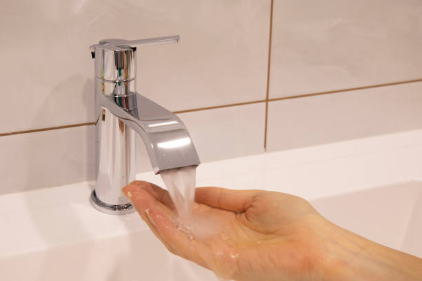 Hand close up with flowing tap water in bathroom
