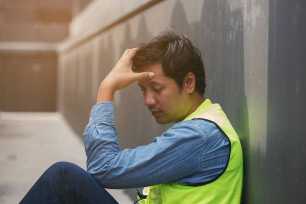istock Asian male worker tired and thirst of water at construction site. Construction builder worker sitting and feel sick, have a headache. Health safe of work and safety first concept 2194704327
