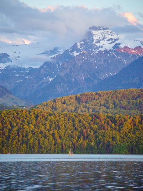 Switzerland scene of a sailboat on a lake with mountains