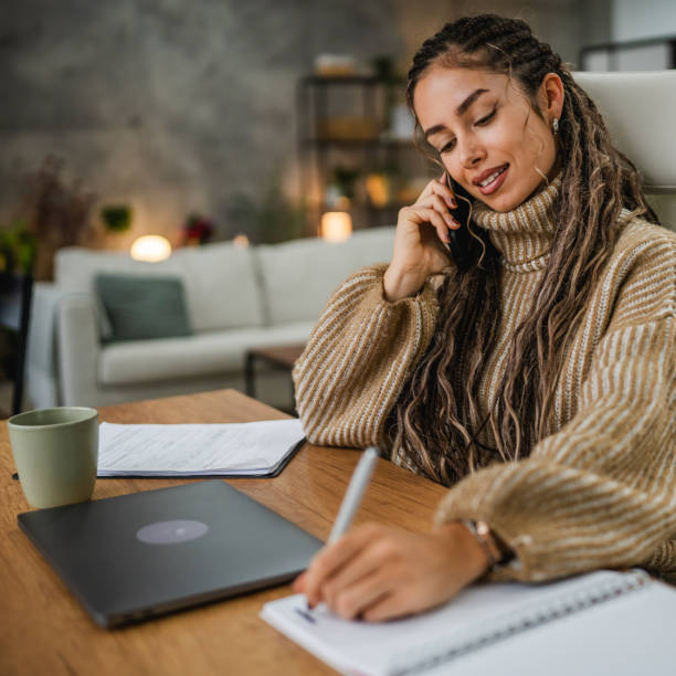 istock young woman work on laptop and talk on cellphone with client at home 2194708961