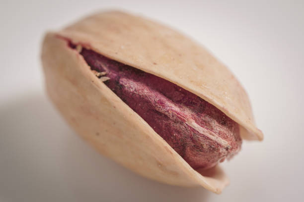 A close-up shot of a pistachio nut inside its shell, showing the vibrant purple seed inside and the cracked shell.