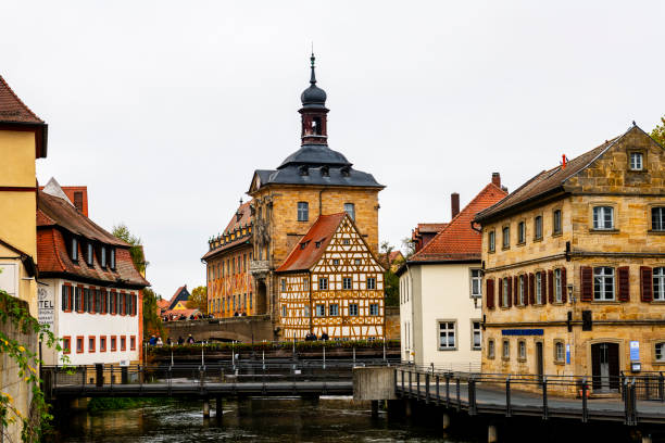 Bamberg, Germany - November 01, 2024: some tourists are on a footbridge over Regnitz River in Bamberg in bavaria in Germany. In background is the famous city hall.