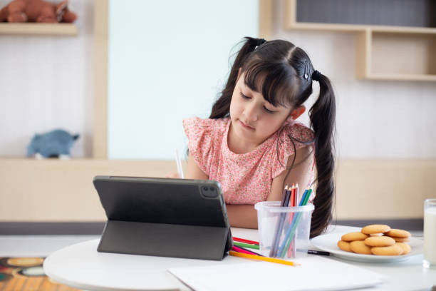 istock Little girl doing homework with modern tablet at home 2194726099