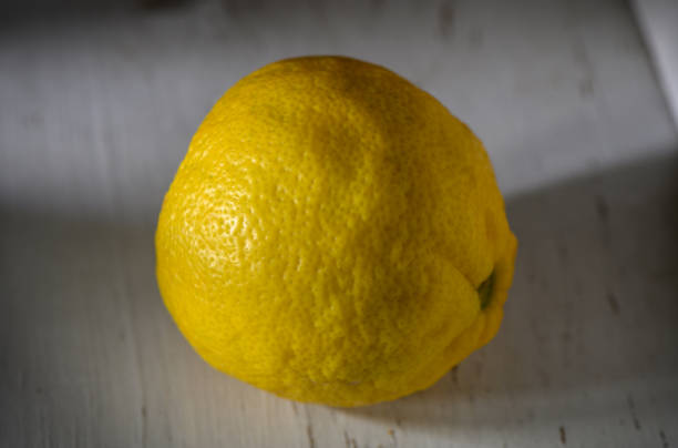 istock Bright yellow lemon rests on a rustic wooden surface in warm natural light 2194728230