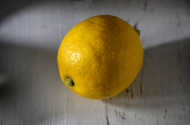 istock Bright yellow lemon resting on a rustic wooden surface under soft natural light 2194728235