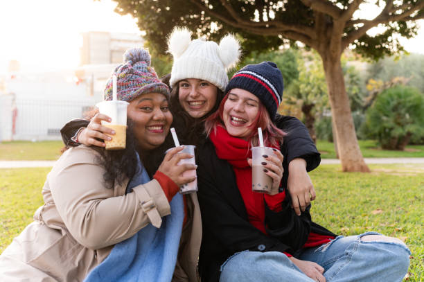 istock Three young women smiling and drinking bubble tea outdoors in a park 2194729066