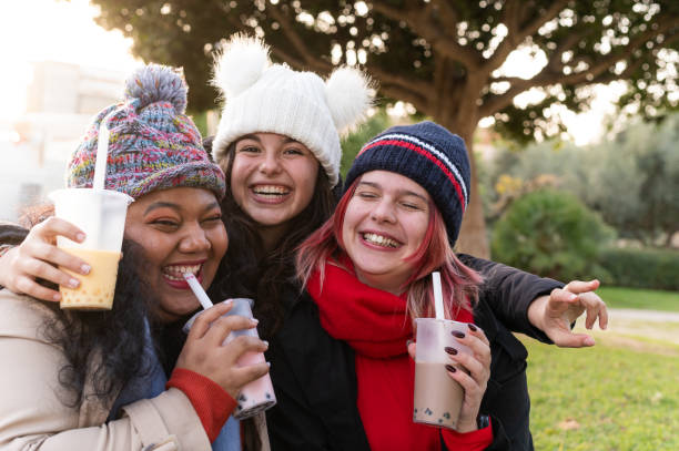 istock Three young women laughing together and drinking bubble tea outdoors 2194729072
