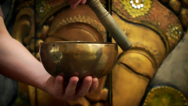 istock Hands playing tibetan singing bowl in front of buddha statue 2194730262
