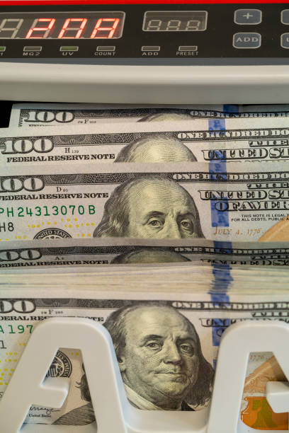 istock Cash counting machine displaying stacked hundred dollar bills in use 2194730580