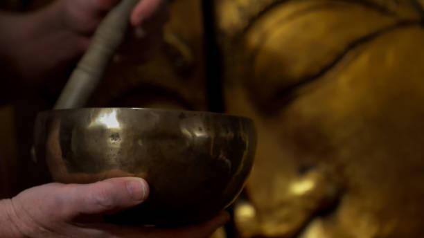 istock Playing tibetan singing bowl in front of buddha statue 2194731333
