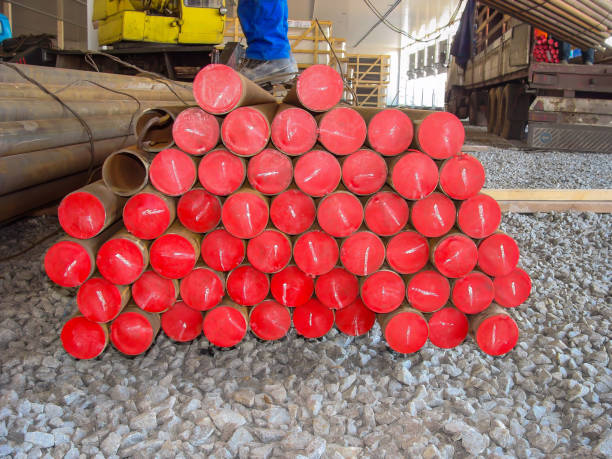 istock Stacked steel pipes with red plastic caps on ends, organized in a pyramid shape at a construction site. 2194731376