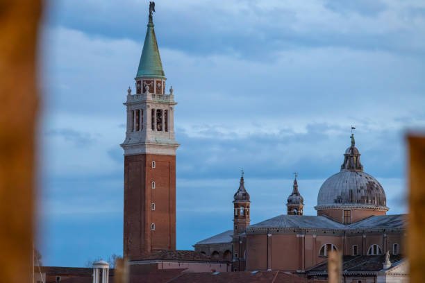 A framed view of the iconic bell tower and domes of San Giorgio Maggiore in Venice, Italy. The architectural beauty stands out against the serene evening sky, capturing the timeless charm of Venetian landmarks.