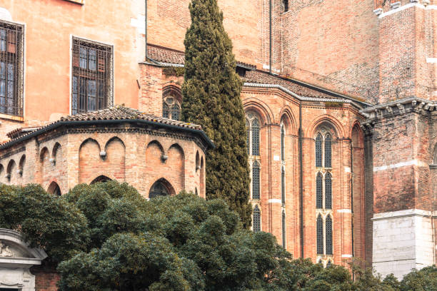 A beautiful close-up of a Gothic-style church facade in Venice, Italy, surrounded by lush greenery and architectural details. The elegant arches and warm tones highlight the timeless beauty and cultural richness of Venetian history.