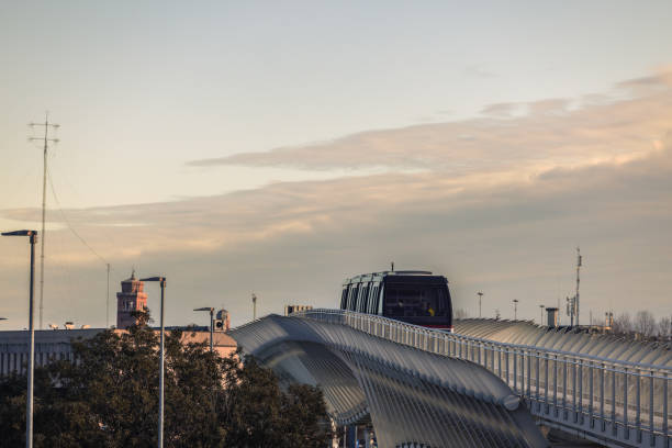A sleek, modern tram travels along an elevated track in Venice, Italy, during a tranquil sunset. The image highlights the blend of modern infrastructure and serene urban landscapes with soft golden-hour lighting.