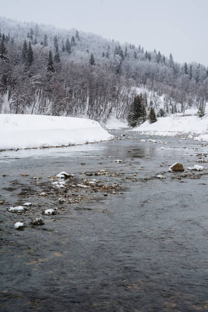 istock A serene river gracefully flows through a picturesque snowy forest, while majestic mountains stand tall in the background, together creating a breathtaking winter landscape that captivates 2194741827
