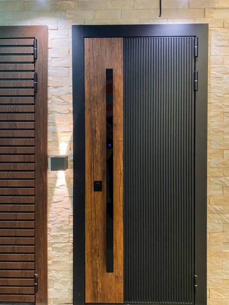 There is a striking black door that features a wooden handle right next to a sturdy brick wall, creating a contrasting yet harmonious visual effect between the surfaces around it