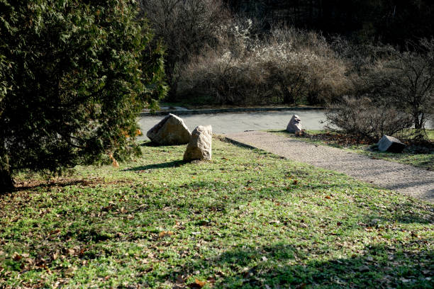 A calm setting features stones by a serene lake, surrounded by autumn foliage.