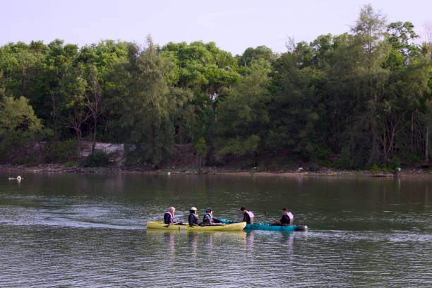 Terengganu, Malaysia - May 31, 2024 : A group of people enjoying a peaceful kayaking trip on a calm river, surrounded by lush green forest. The serene outdoor setting captures the beauty of nature and recreational activities.