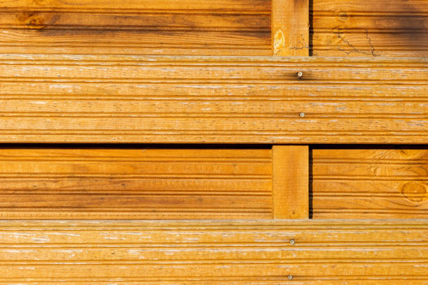 Warm-toned wooden panels exhibit a textured surface with pronounced lines and grooves, creating a rustic aesthetic ideal for construction and design applications.