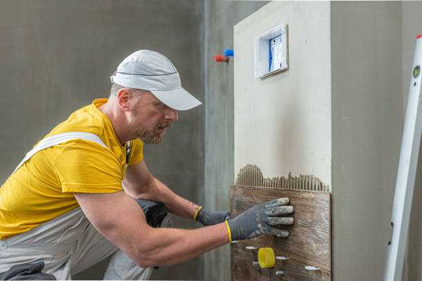 istock Tiling work in the bathroom.  Tiler while tiling build-in cistern. 2194752235