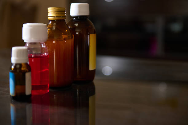 An assortment of small medicine bottles with different contents placed on a wooden table surface.