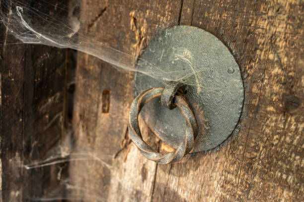 Spider webs over very old metal door lock on wooden door