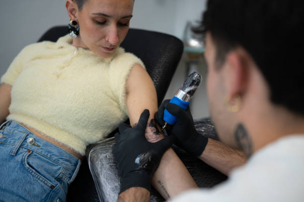 istock Professional tattoo artist drawing detailed cat design on client's arm, working with precision in clean studio environment 2194756740
